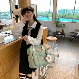Detail of light green canvas backpack with plush flower pendant in a cafe setting