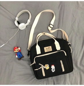 Detailed view of black canvas tote bag with adjustable straps and cute decorative pins