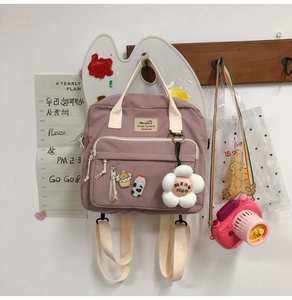 Close-up of pink canvas bag with cute charms and a brand label on a wooden hook