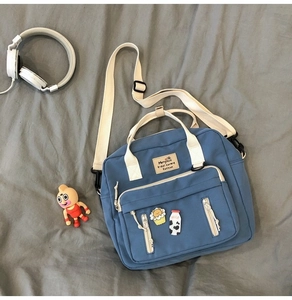 Blue canvas crossbody bag with adjustable straps and cute cartoon badges on front pocket