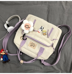 Detail of cream canvas tote bag with purple straps and cute badges on grey fabric