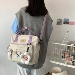Detail of cream canvas tote with purple straps and cute charms shown on model