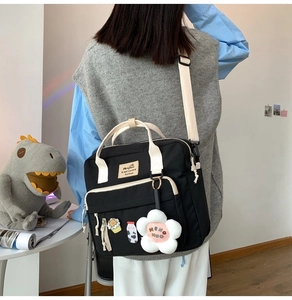 Detail of black canvas tote bag with floral pendant and cute pins worn as crossbody