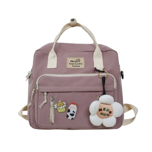 Detail of pink canvas backpack with cute pins and soft plush flower keychain accessory