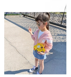 Detail shot of a yellow car-shaped kid crossbody bag with police print and red star logo
