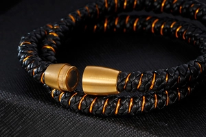 Gros plan du fermoir magnétique doré et du bracelet en cuir tressé noir pour hommes
