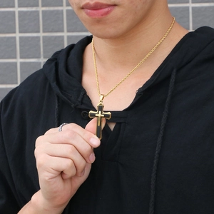 Men's gold and black layered cross pendant necklace on a twist chain worn by model