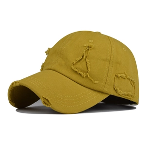 Detail of distressed brim and torn fabric on a yellow washed cotton baseball cap