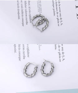 Macro shot of silver twisted metal hoop earrings on vintage printed paper background