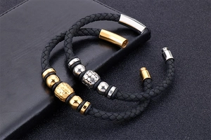 Detail of woven leather bracelets with silver and gold magnetic clasps on black texture