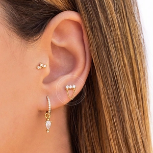 Detailed view of gold triple-zircon stud earring with fine chain and flower accents
