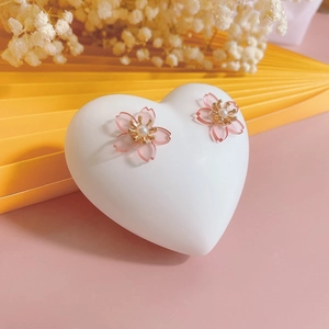 Pink cherry blossom stud earrings with pearls on a heart-shaped jewelry display stand