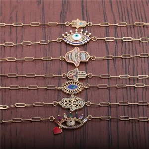 Hip Hop Evil Eye and Hamsa Hand bracelets with colorful zircons on wood background