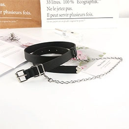 Detail eines schwarzen Punk-Gürtels mit Herzanhänger und silberner Metallkette