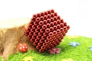 Macro detail of 5mm red magnetic balls arranged in a cube on a miniature grass display