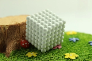 Detailed macro view of 216 white magnetic 5mm balls arranged in a cube on miniature turf
