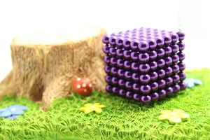 Macro shot of 5mm purple magnetic balls in a cube shape on a miniature forest background