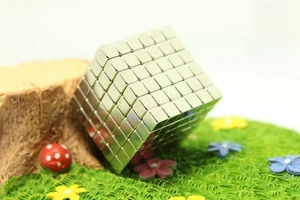 Macro shot of silver magnetic cubes stacked on miniature artificial grass and moss