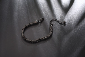 Detailed view of a black stainless steel herringbone chain bracelet with lobster clasp