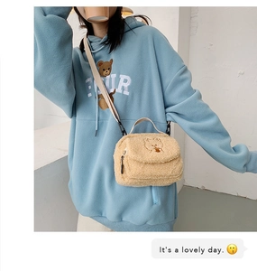 Cute teddy bear embroidery on plush crossbody bag shown worn with a blue hoodie