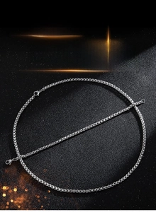 Detailed view of men's silver box chain necklace and bracelet set on a black background