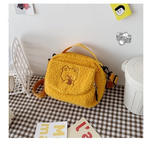 Close-up of yellow plush crossbody bag with cute teddy bear embroidery and nylon strap