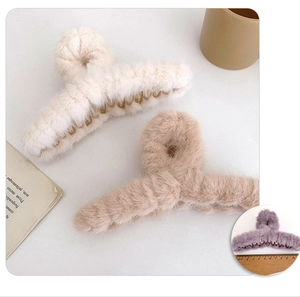 Detailed close-up of large plush hair claw clips in cream and light brown faux fur