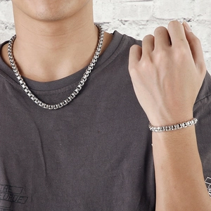 Ensemble collier et bracelet pour homme en acier inoxydable argenté porté par un mannequin