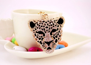 Detailed macro of leopard head keychain encrusted with white crystals and gold finish