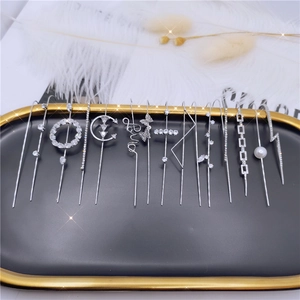 Macro shot of silver zircon ear crawlers with butterfly and heart charms on a black tray