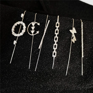 Detailed macro shot of various silver rhinestone ear cuffs and climbers on black background