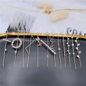 Detailed flat lay of golden zircon ear cuffs with butterfly and LOVE motifs on a tray