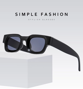 Detail of rectangular black sunglasses with blue-gray lenses on a geometric display