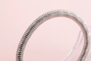 Macro shot of silver stainless steel spiral spring bracelet on a clear acrylic stand