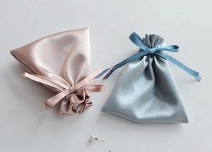 Detail of satin drawstring gift bags with pearl texture and elegant silk ribbon bows