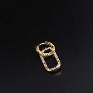 Macro shot of gold hoop earring with rectangular pendant and sparkling zircon stones