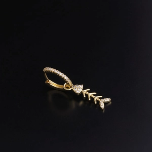 Detailed view of gold fishbone earrings with sparkling zircon stones on black background