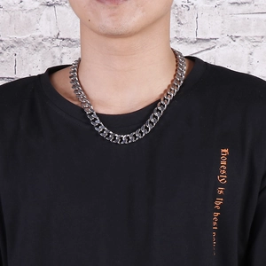 Close-up of thick silver Cuban chain necklace on male model wearing a casual t-shirt