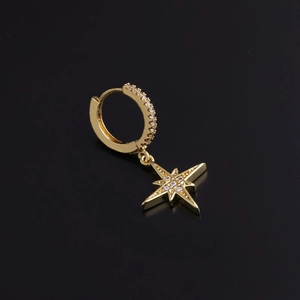 Detail of a gold hoop earring with a sparkling zircon octagon star pendant on dark background