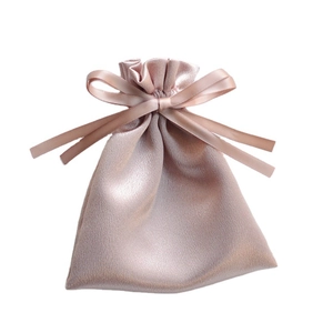 Glossy champagne satin drawstring gift bag with elegant silk ribbon bow on white background
