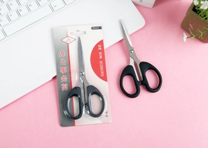 Macro detail of black stainless steel office scissors with retail blister card packaging
