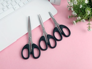 Three heavy duty black stainless steel scissors on a minimalist pink office desktop