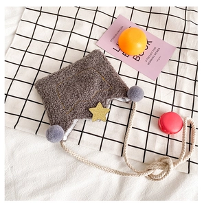 Detail of plush gray crown bag featuring yellow stars, purple pom-poms and rope strap