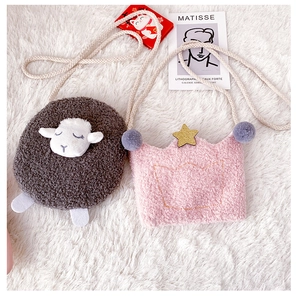 Detailed close-up of gray lamb and pink crown plush bags on a soft white carpet
