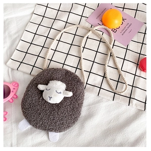 Detail of plush lamb crossbody bag with soft faux fur texture on a cozy plaid background