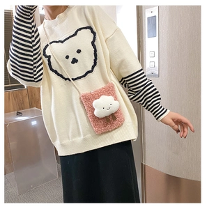 Detail of white fleece cloud bag with cute bear pattern on a knitted sweater