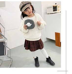 Detail of plush cream lamb wool sweater and brown plaid pleated skirt for girls
