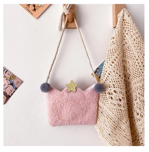 Pink plush crown bag with gold sequins and grey pom pom hanging on a wooden hook