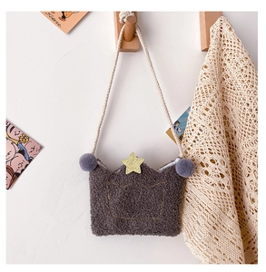 Detail of plush crown-shaped children crossbody bag with golden stars and purple pom-poms