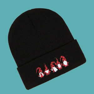 Close-up of black knit beanie featuring festive Nordic gnome patterns on the folded cuff